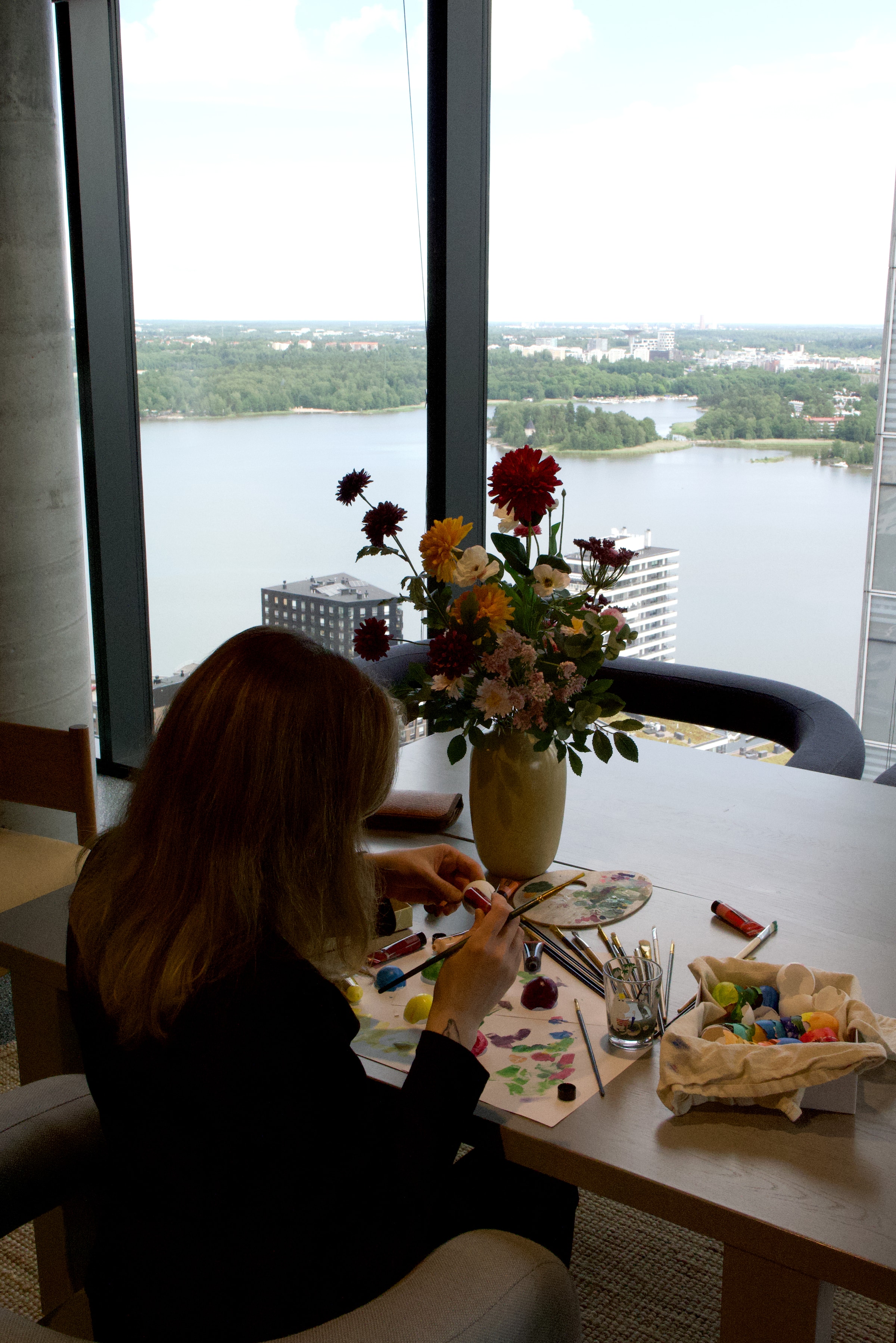 Artist working by a large studio window with a Helsinki view