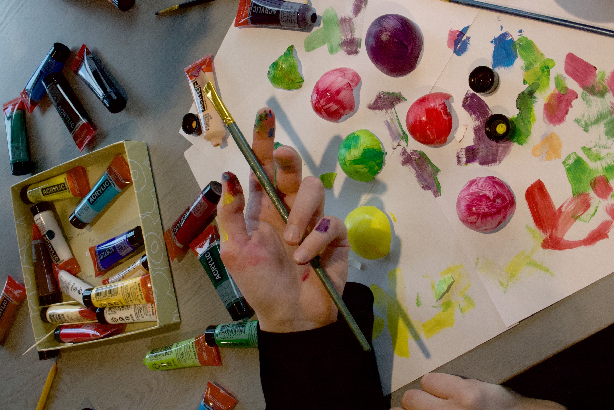 Over-the-shoulder — artist sketching beside a sheet of hand-dyed eggshell colour samples